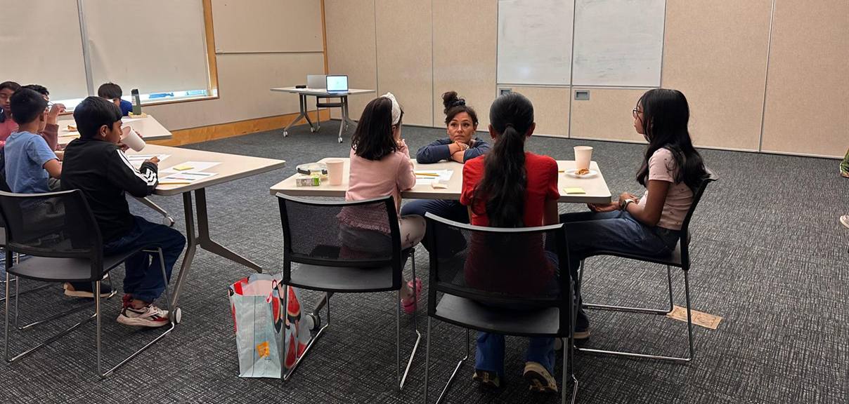 A Situation Room cohort in discussion around the table with facilitator Natalie DuKane